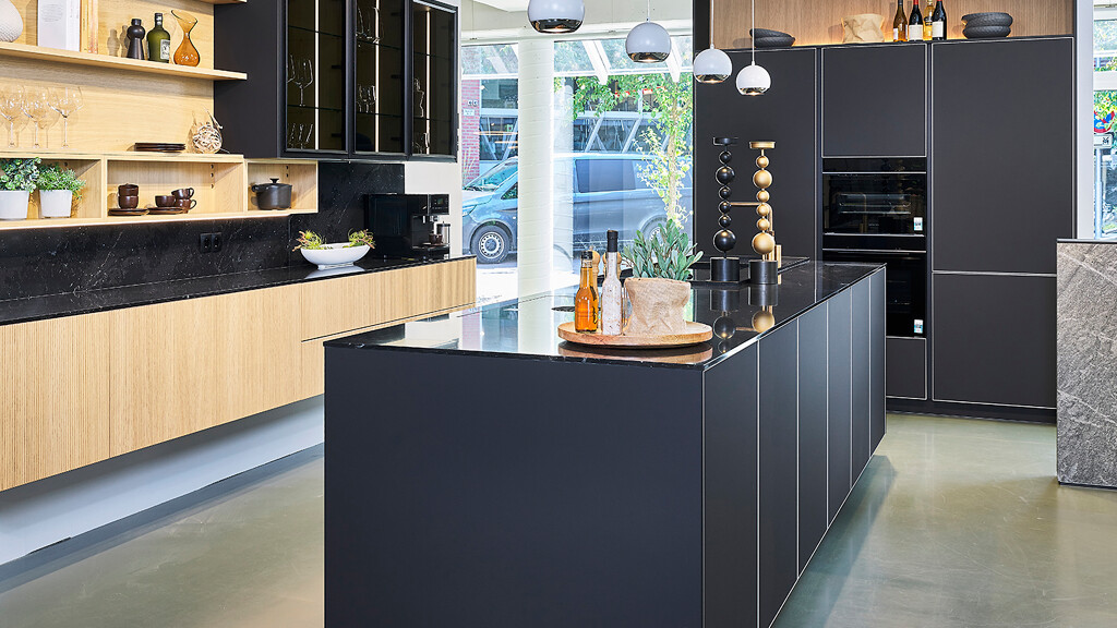Chique Ballerina keuken met zwarte ALU TEC Fronten, vitrine bovenkasten en eiken TALEA Ribbelfronten. Te bewonderen in Küchenhaus Ekelhoff in het centrum van Nordhorn