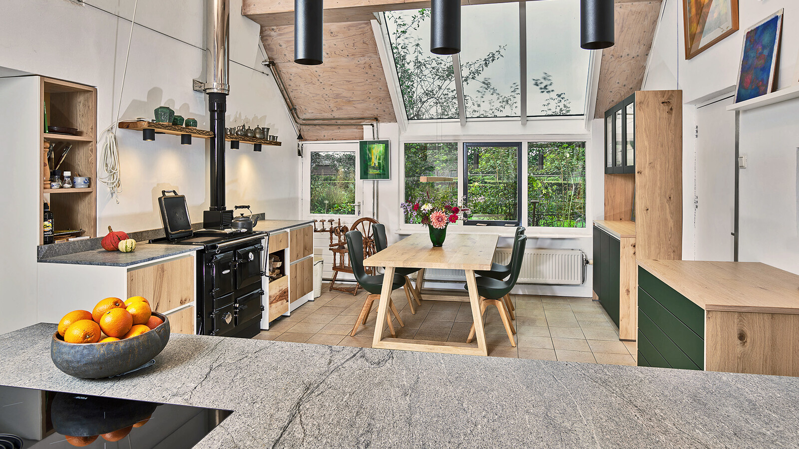 Landelijke keuken van Contur met fronten in licht eiken fineer en matgroen. Het keukenblad is van Blue Sky graniet.