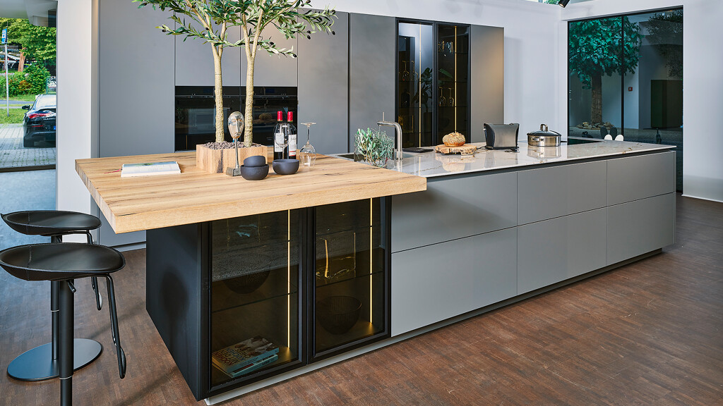 Zandgrijze keuken van Ballerina Keukens met kookeiland, vitrinekasten en barplaat. Bij Ekelhoff Keukens in Nordhorn