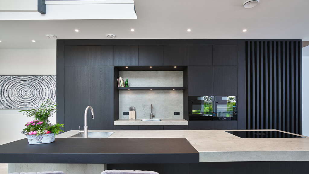 Een maatwerkkeuken in donker eiken met spoelnis en keramisch werkblad.