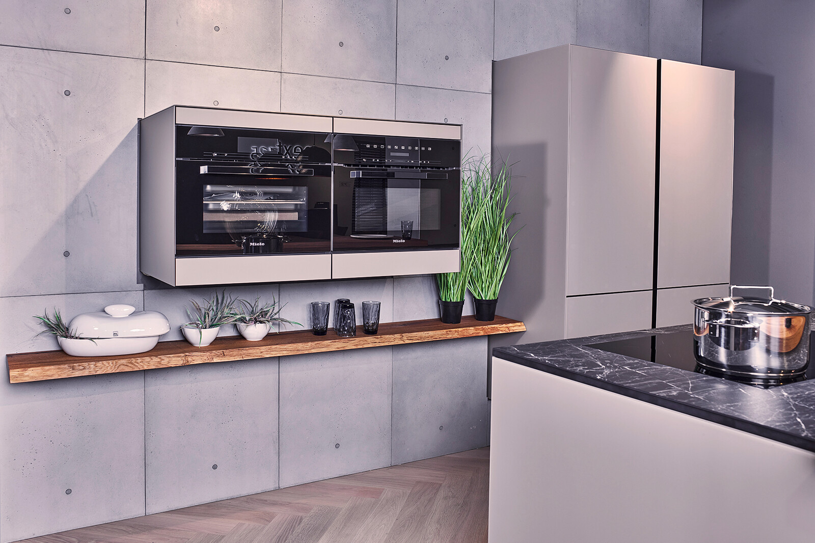 Showroomkeuken: next125 compacte industriële eilandkeuken met matglas fronten en gaggenau ovens