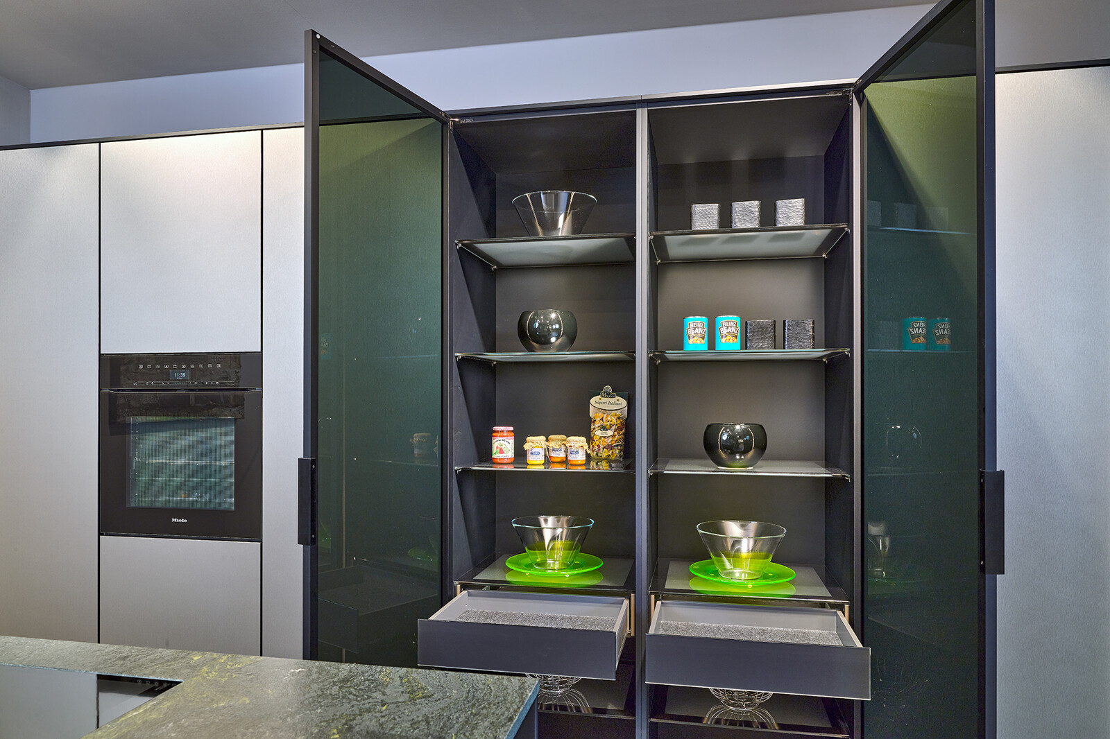 Showroomkeuken: next125 designkeuken in metallic Inox SensiQ en vitrinekast zwart glas