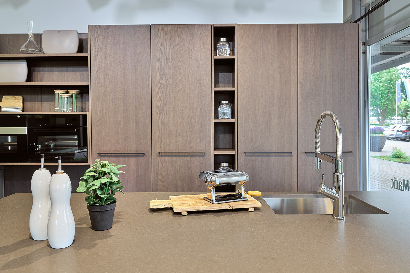 Showroomkeuken: SieMatic designkeuken met kiezelgrijs keukeneiland en Hazelbrown eikenfineer kastenwand