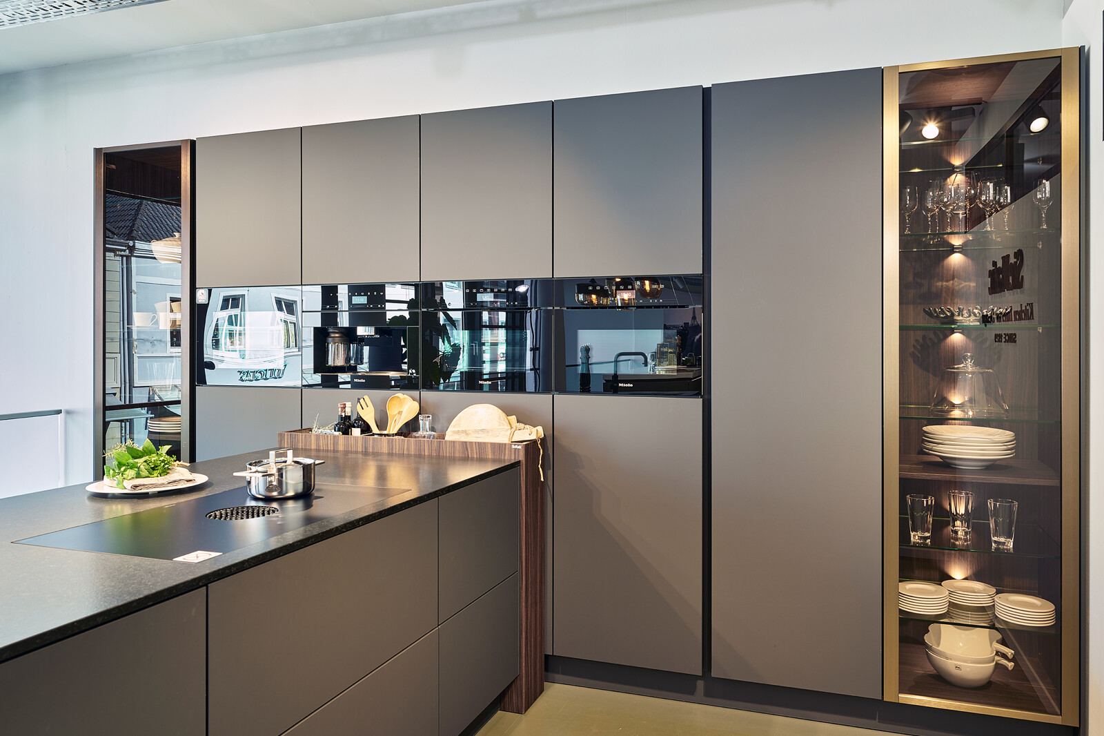 Showroomkeuken: SieMatic S2: grijze keuken met schiereiland, vitrinekasten en Miele apparatuur