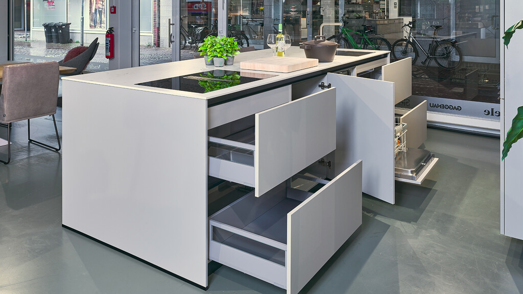 Keuken kopen: eilandkeuken in kiezelgrijs en donker eiken (im.). Het werkblad is van keramiek in marmerlook, aan het eiland is plaats voor 2 barkrukken.