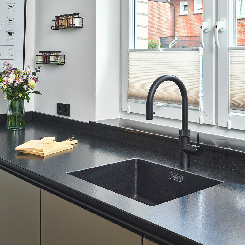 Keuken met zwarte spoelbak enQuooker. Kleine keuken met kookeiland. next125 keuken NX912 met matglas fronten in Platina metallic. Thuis bij keukendesigner Benjamin Cicek van Ekelhoff Keukens in Duitsland