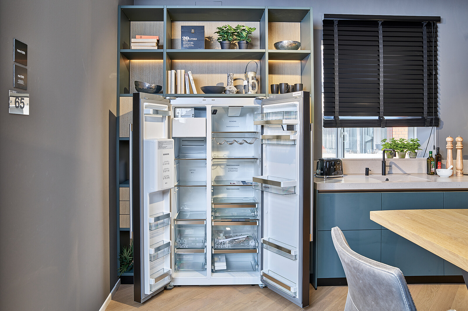 Showroomkeuken: Groene next125 designkeuken met  amerikaanse koelkast van Siemens en open kast met verlichting