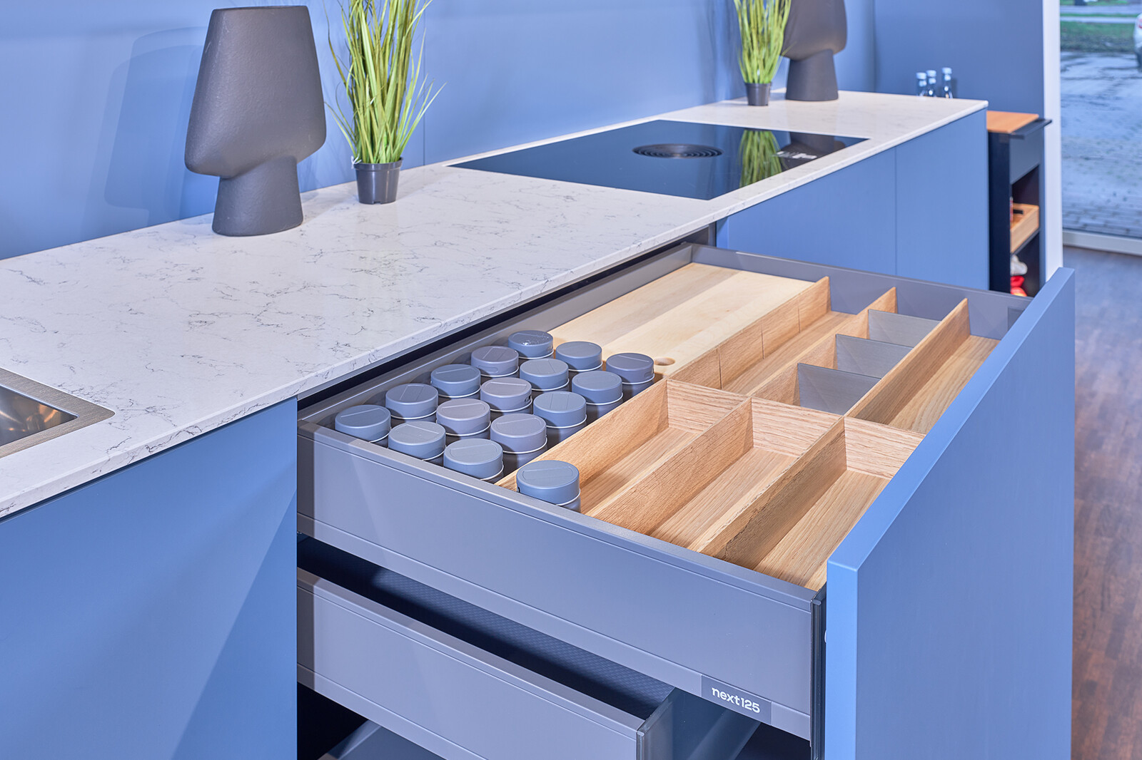 Showroomkeuken: next125 Blauwe designkeuken met wit marmerlook keukenblad en luxe lade-inrichting