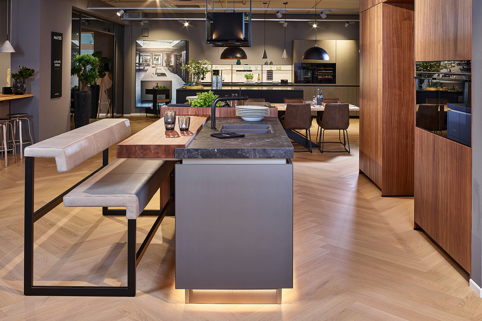 Showroomkeuken: next125 design eilandkeuken met bar in notenhout en matglas met plintverlichting 