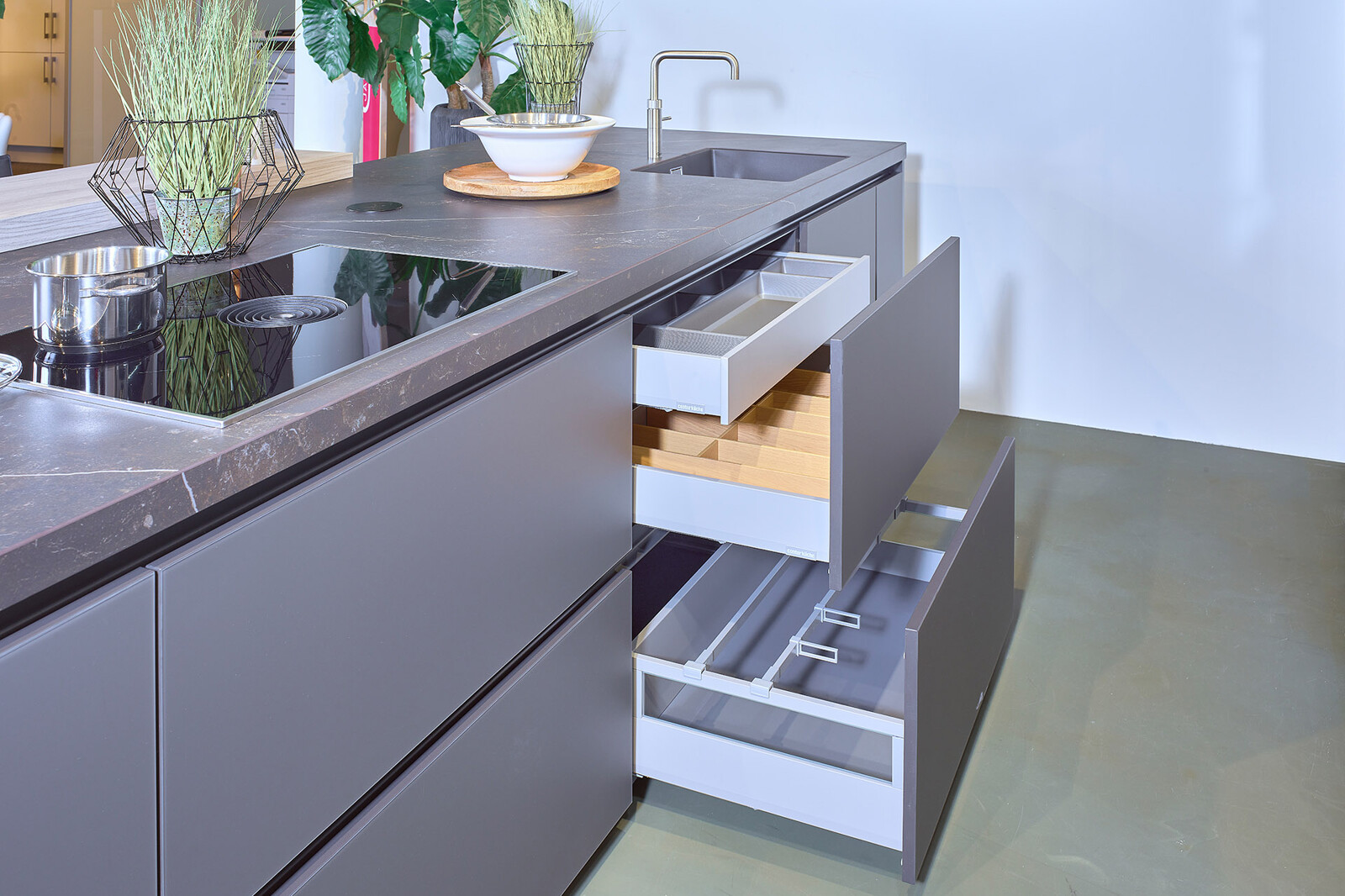 Showroomkeuken: zwarte eilandkeuken met houten kastenwand van Contur met veel brede lades