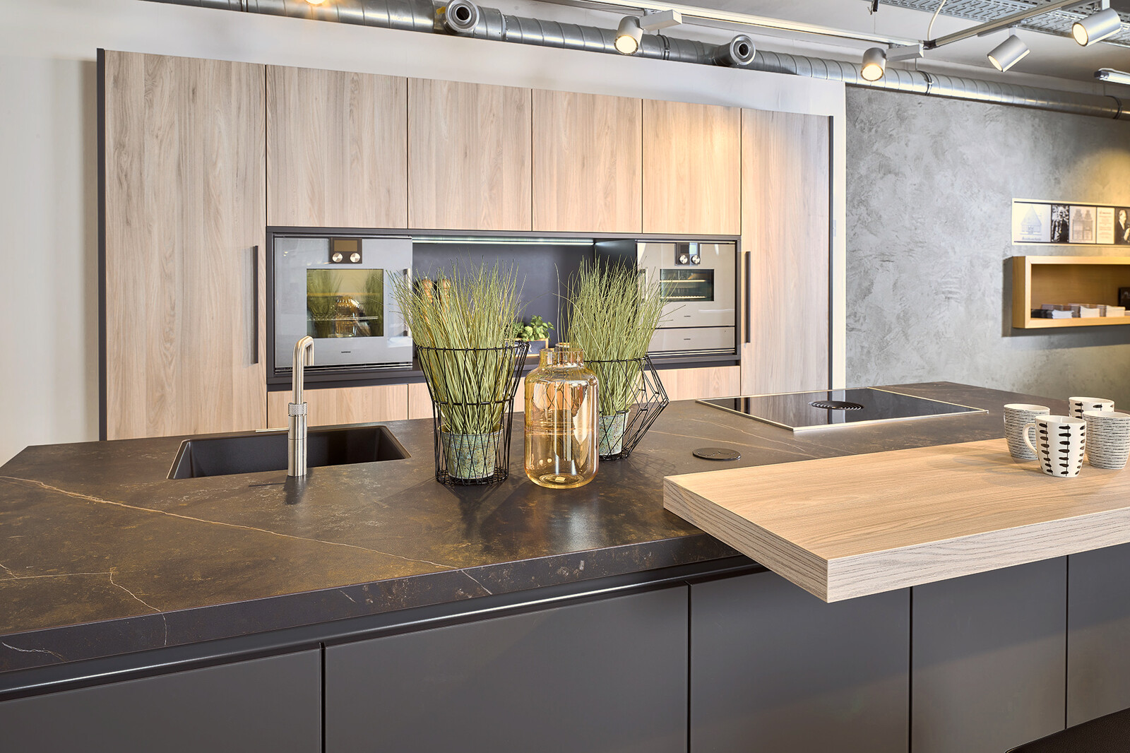 Showroomkeuken: Zwarte eilandkeuken met houten kastenwand en Dekton keukenblad
