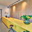 Zonnige gele keuken - eilandkeuken met ruimte voor barkrukken en een houten kastenwand van vloer tot plafond