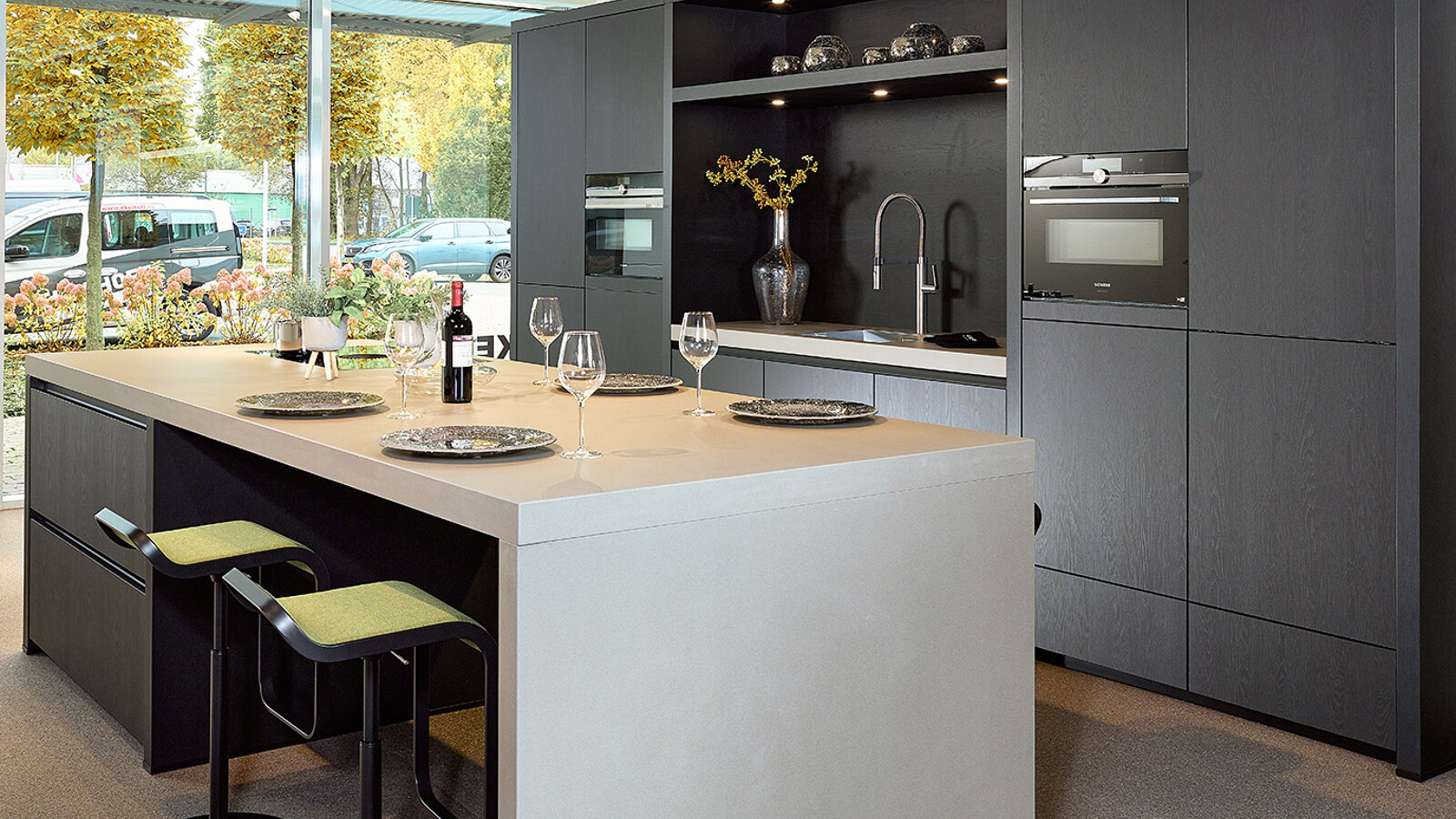 Deze keuken met nis in de kastenwand is een zwarte eilandkeuken van Contur met een keramiek keukenblad