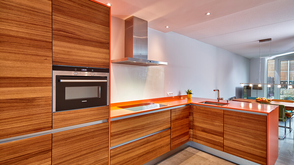 Keuken met teakhouten fronten en oranje composiet werkblad Ekelhoff Keukens