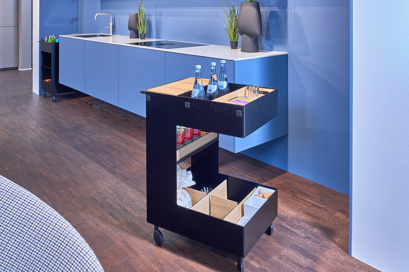Showroomkeuken: next125 Blauwe designkeuken met wit composiet werkblad en keukentrolley