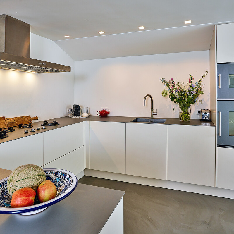 Greeploze u-keuken in magnolia met rvs keukenblad en Gaggenau apparatuur van Ekelhoff Keukens.