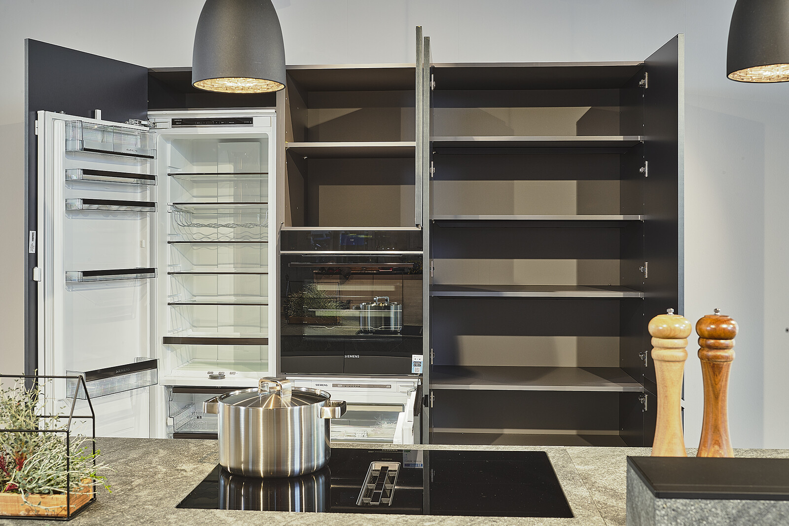 Valcucine showroomkeuken met granieten werkblad, zwarte hoge kast en apparatuur van Siemens