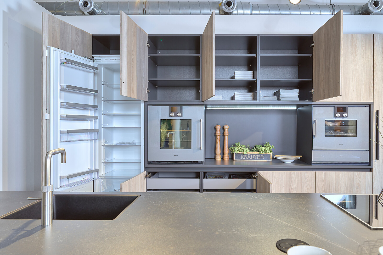 Showroomkeuken: zwarte eilandkeuken van Contur met houten kastenwand en Neff apparatuur