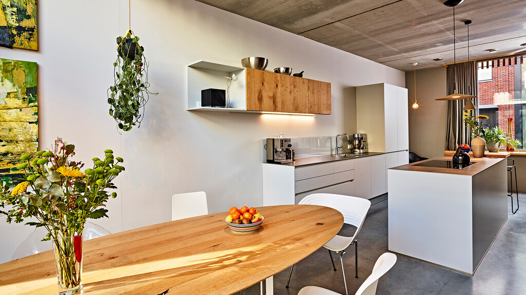 Eettafel met stoelen en Contur eilandkeuken in mat kristalgrijs en balkeneiken met RVS werkblad in de achtergrond