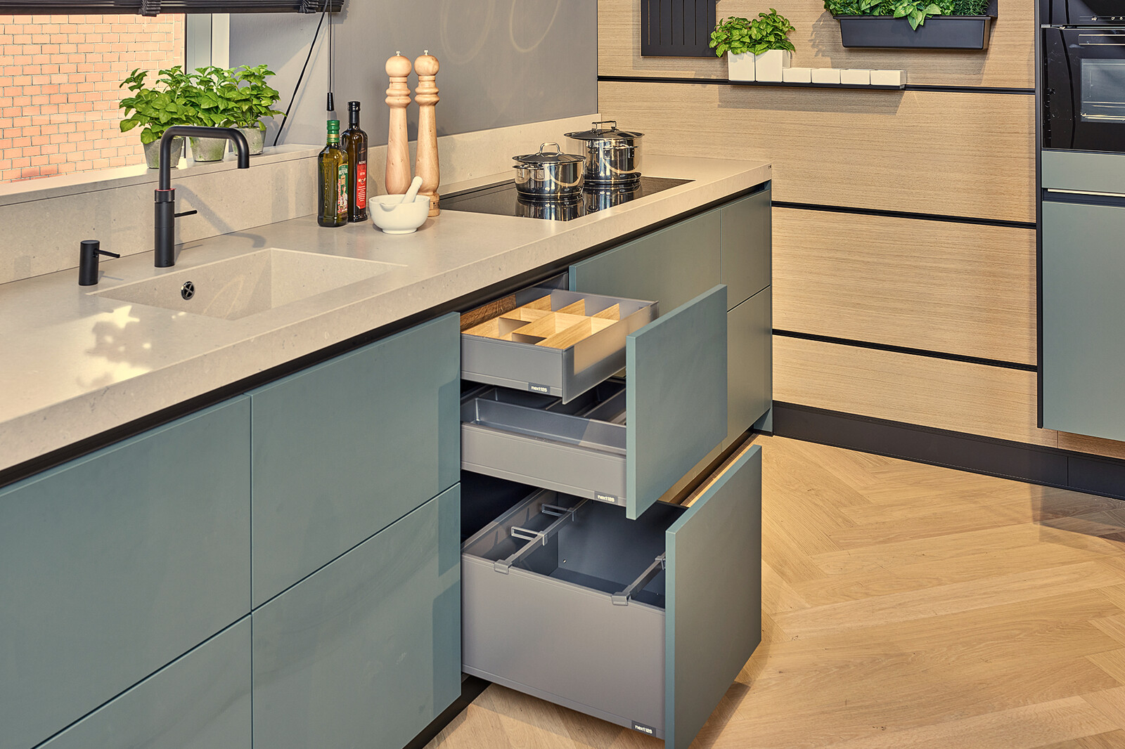 Showroomkeuken: Groene next125 designkeuken met  cube systeem achterwand, zwarte details  en veel lades