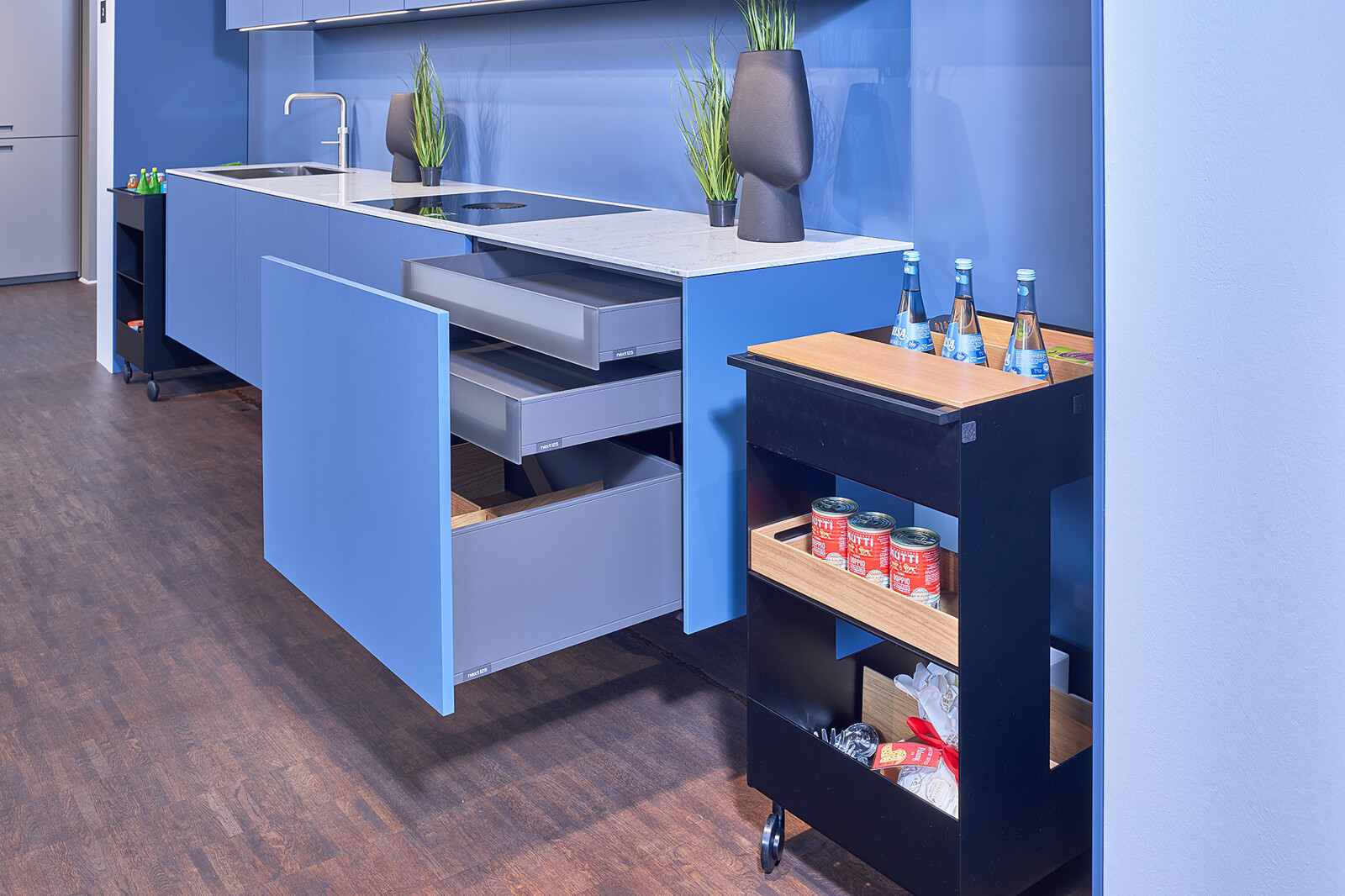 Showroomkeuken: next125 Blauwe designkeuken met wit composiet keukenblad en keukentrolley