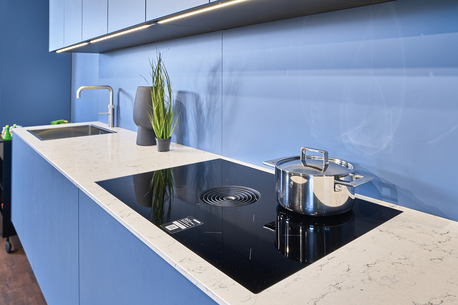 Showroomkeuken: next125 Blauwe designkeuken met wit composiet werkblad en bora kookplaat
