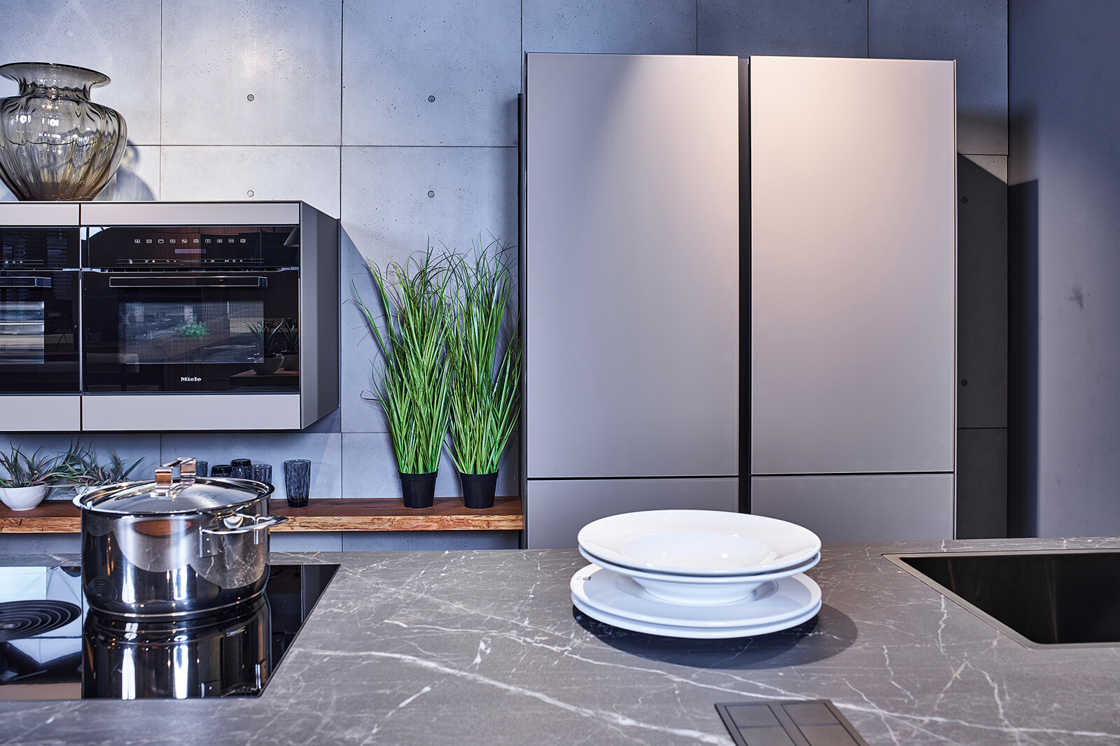 Showroomkeuken: next125 industriële eilandkeuken met matglas fronten, bora kookplaat en gaggenau ovens