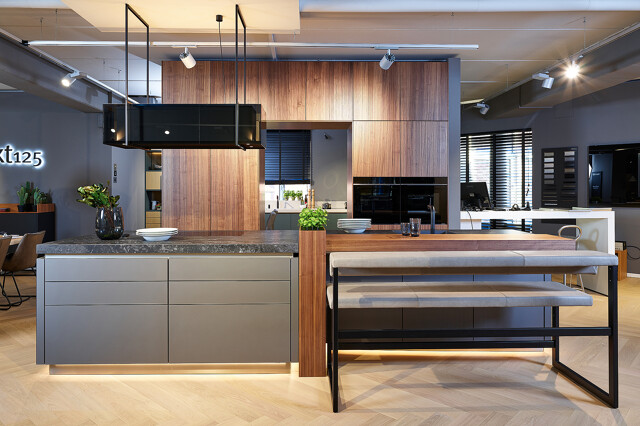 Showroomkeuken: next125 designkeuken met kookeiland in notenhout lamellenfronten en matglas fronten
