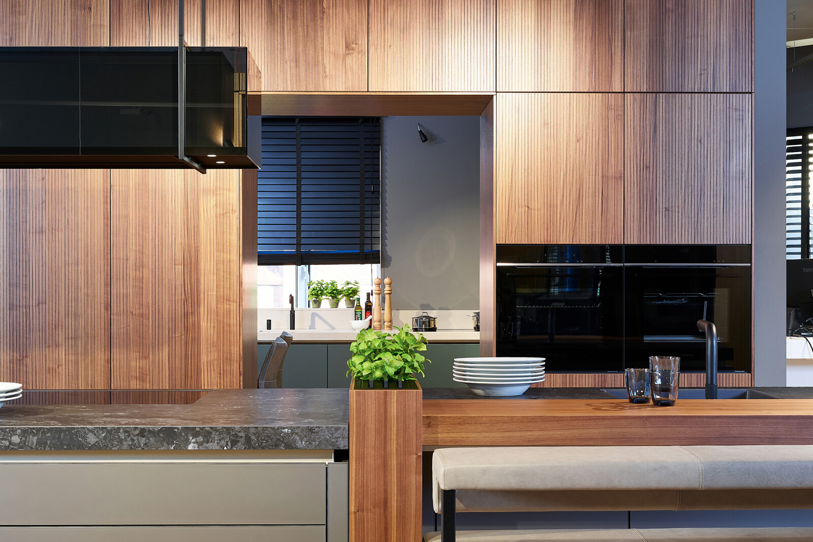 Showroomkeuken: next125 design eilandkeuken met bar in notenhout en matglas met maatwerk elementen