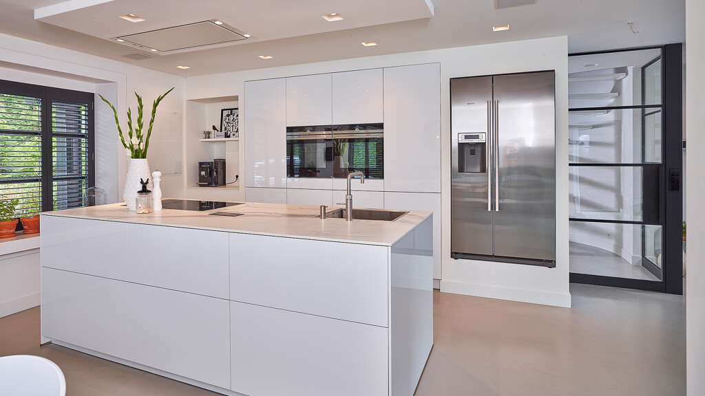 Greeploze eilandkeuken van next125 in hoogglanslak met wit keramiek keukenblad. Lees de keukenreview en bekijk de foto's.