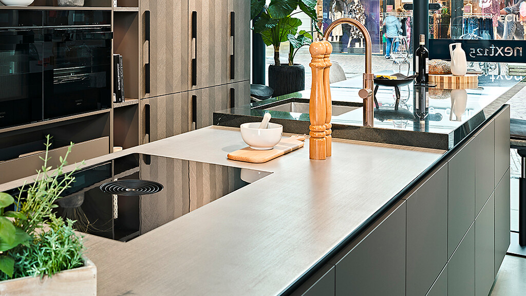 Ballerina Inselküche Intarsia mit einer Küchenarbeitsplatte aus Edelstahl und einer Granitplatte. Zu sehen bei Ekelhoff Küchen in Nordhorn.