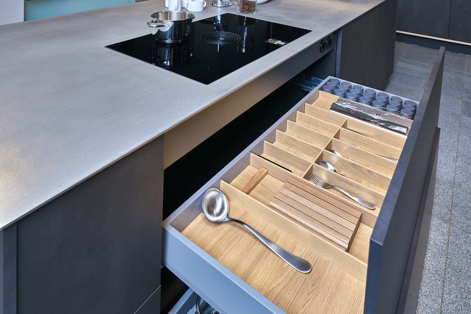 Showroomkeuken: Industriële eilandkeuken van Contur met rvs blad, staallook fronten en luxe houten lade inrichting