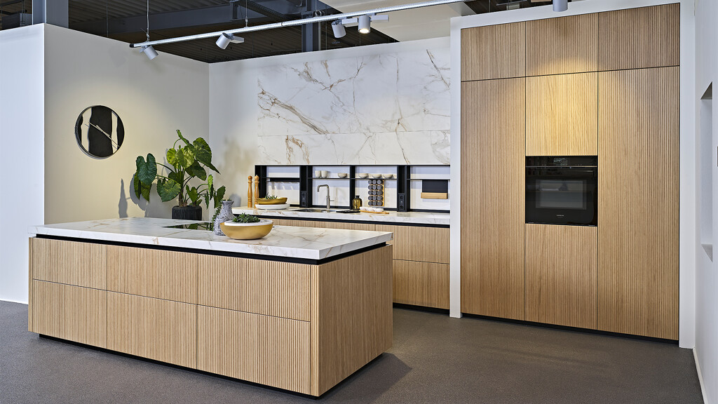 Japandi stijl keuken van next125 met geribbelde lamellenfronten in licht eiken en keramiek werkblad en achterwand. Bij Ekelhofff Keukens, net over de grens in Duitsland.