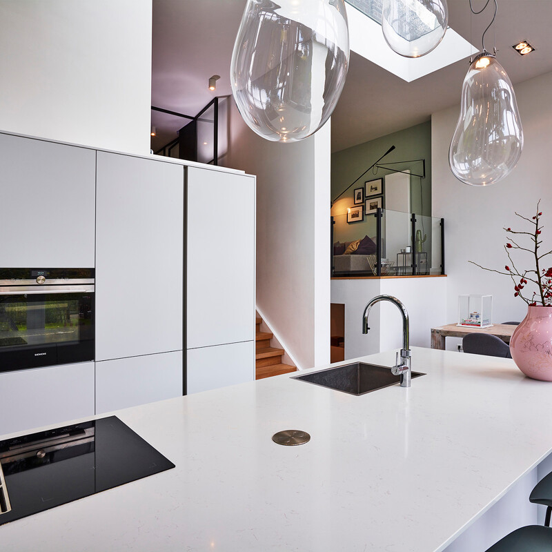 Strakke greeploze eilandkeuken met plaats voor barkrukken, in matwit met wit keramiek aanrechtblad van Ekelhoff Keukens.