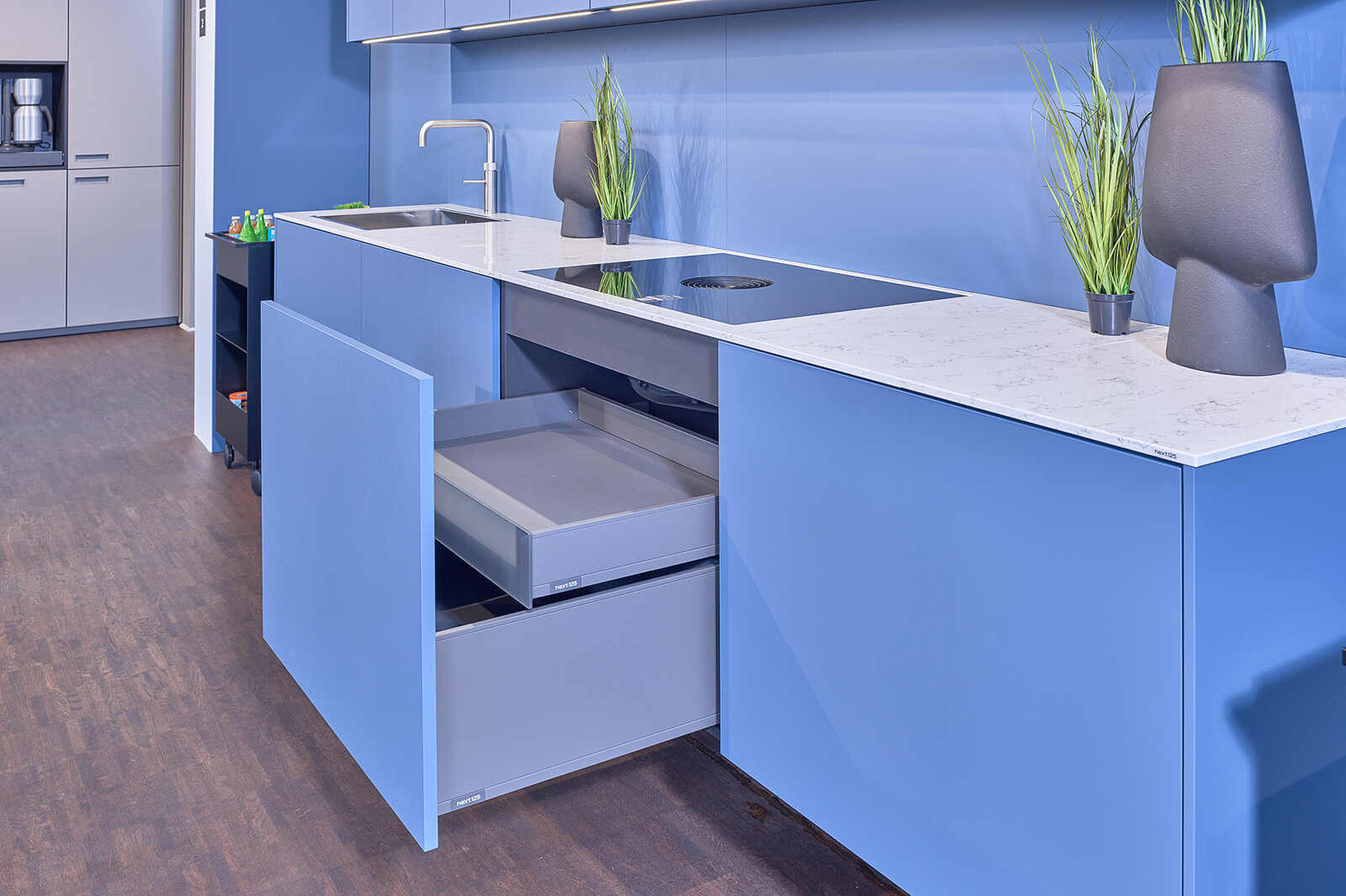 Showroomkeuken: next125 Blauwe designkeuken met wit marmerlook keukenblad en binnenlades