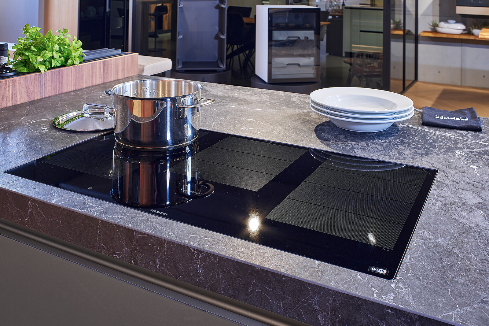 Showroomkeuken: next125 design eilandkeuken met ribbelfronten in notenhout en matglas. Siemens kookveld met flexzones