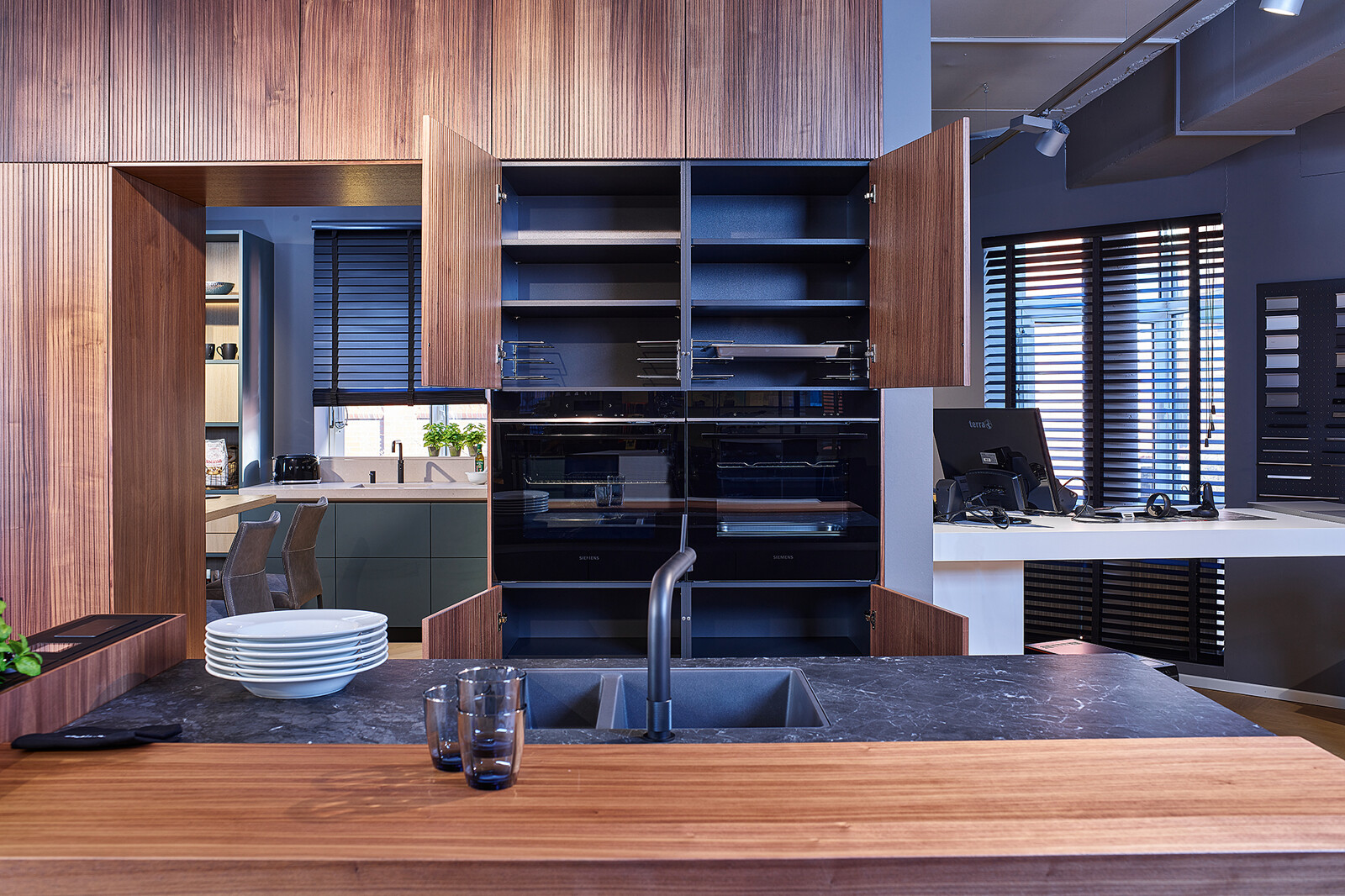 Showroomkeuken: next125 design eilandkeuken met ribbelfronten in notenhout en matglas met lavazwart kastinterieur