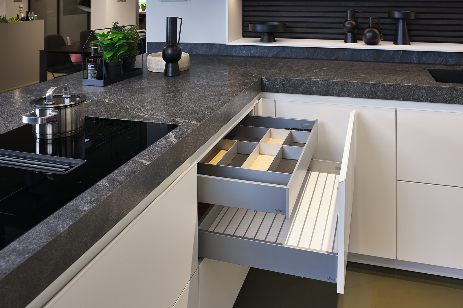 Showroomkeuken: SieMatic Mondial in lotuswit met schiereiland, granieten blad en lades met binnenlades