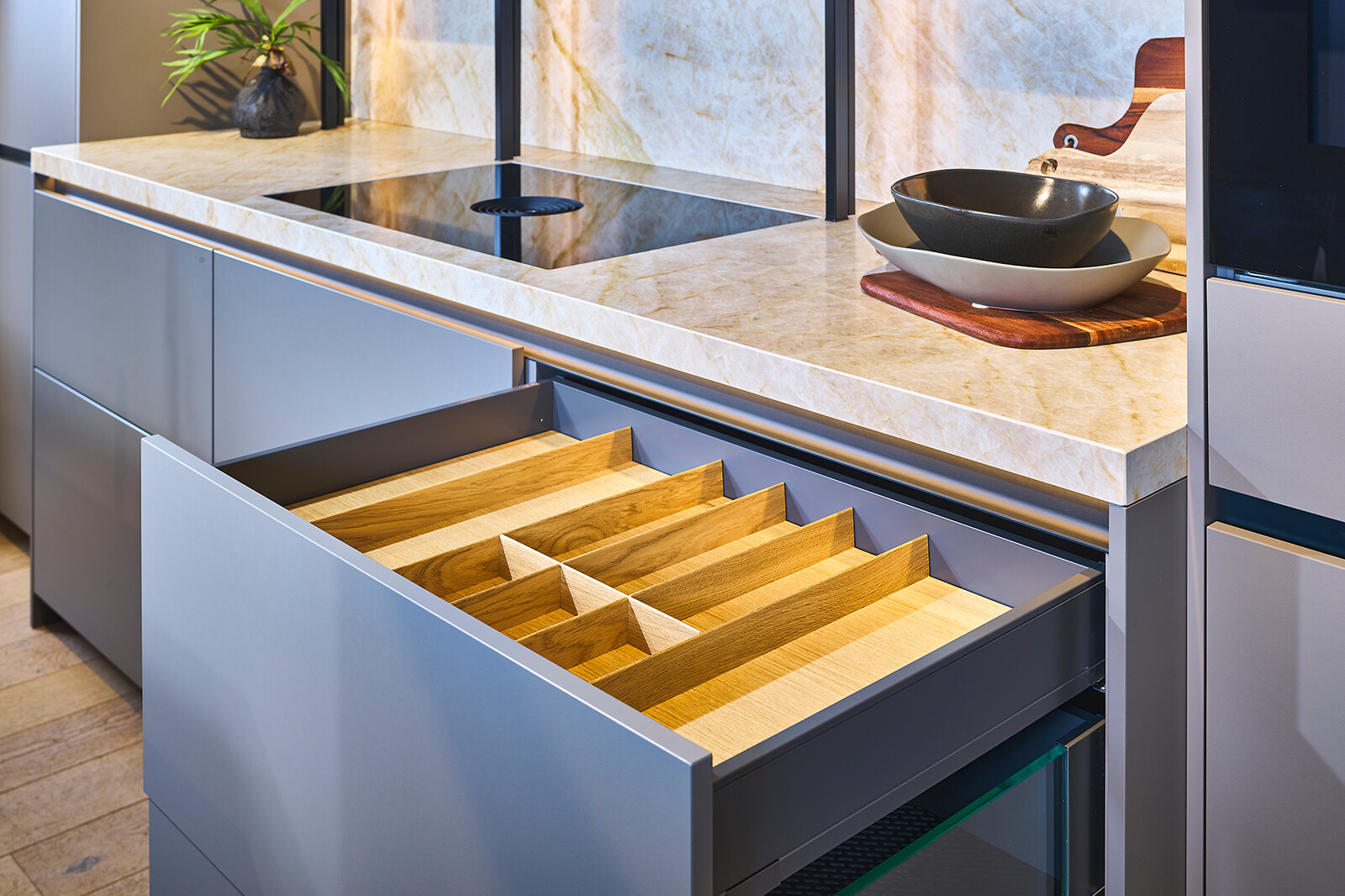 Showroomkeuken: taupe eilandkeuken met veel lades - houten besteklade