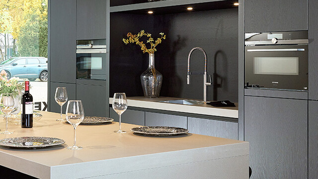 Diese Küche mit Nische in der Schrankwand ist eine schwarze Inselküche von Contur.