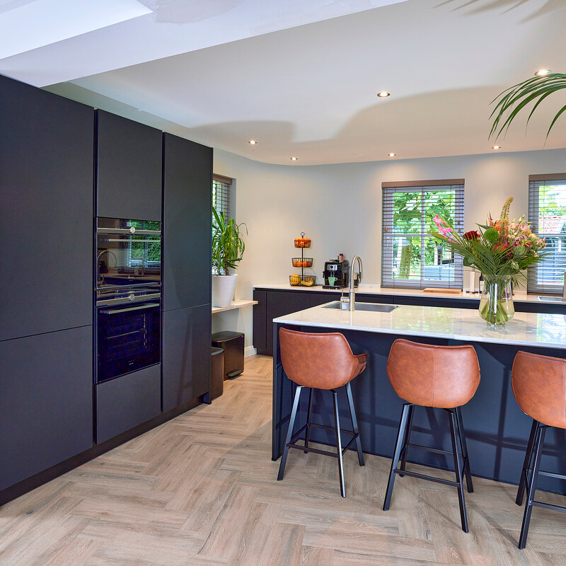 Mattschwarze Küche mit Insel und weißer Arbeitsplatte in Marmoroptik