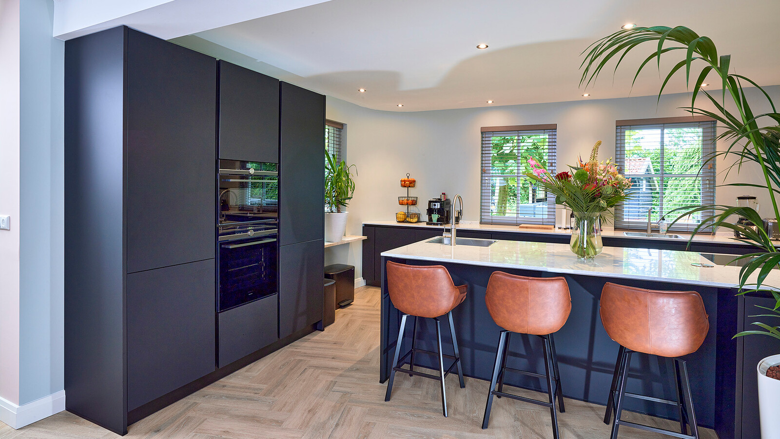 Mat zwarte keuken met eiland en wit marmerlook blad