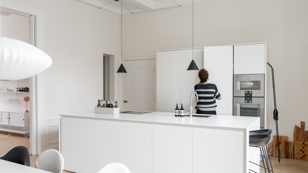 Een witte keuken met nis en gesloten pocket deuren. Mies Interieur, Charlotte Kap Fotografie
