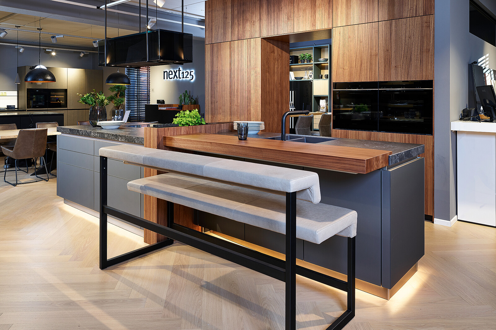 Showroomkeuken: next125 designkeuken met kookeiland in notenhouten matglas met bar
