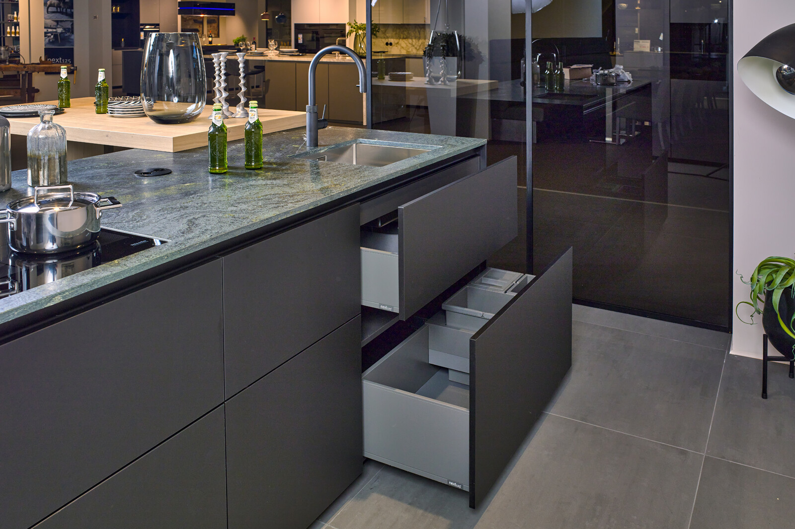 Showroomkeuken: next125 designkeuken in SensiQ met groen graniet blad en brede lades