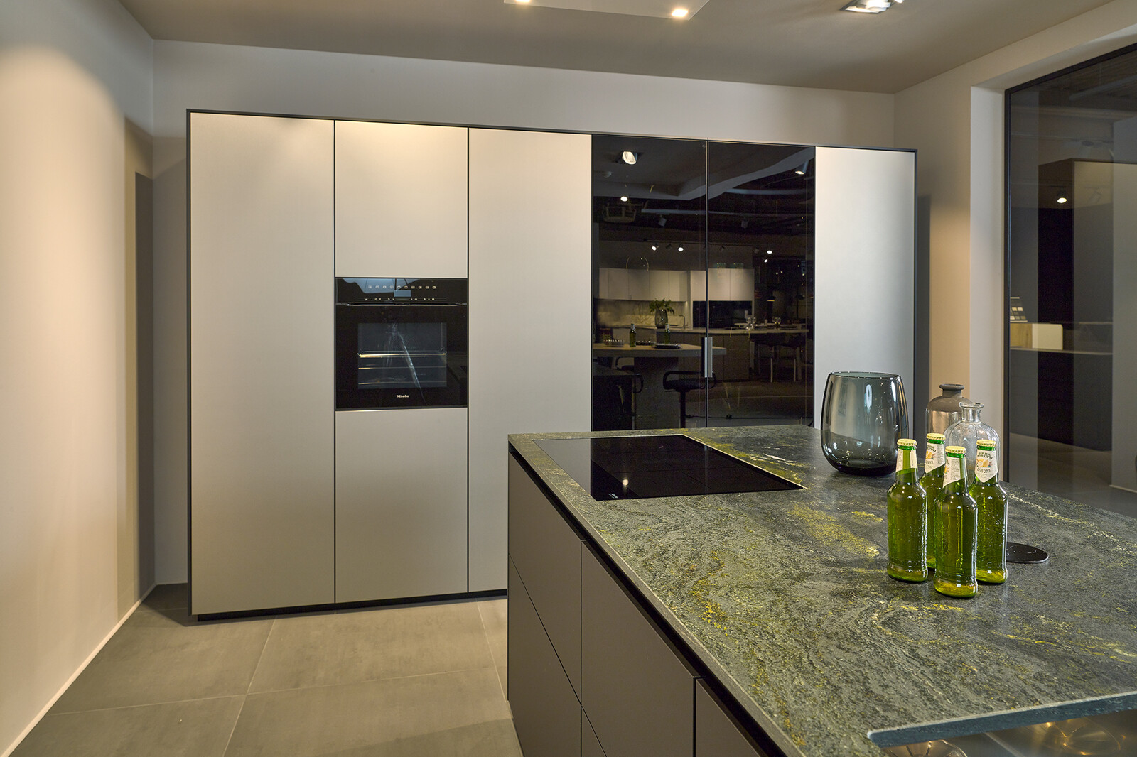 Showroomkeuken: next125 designkeuken met groen granieten keukenblad, inox metallic fronten en vitrinekasten