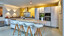 Next125 Küche mit weißen Mattglasfronten und Kücheninsel mit vier Barhockern