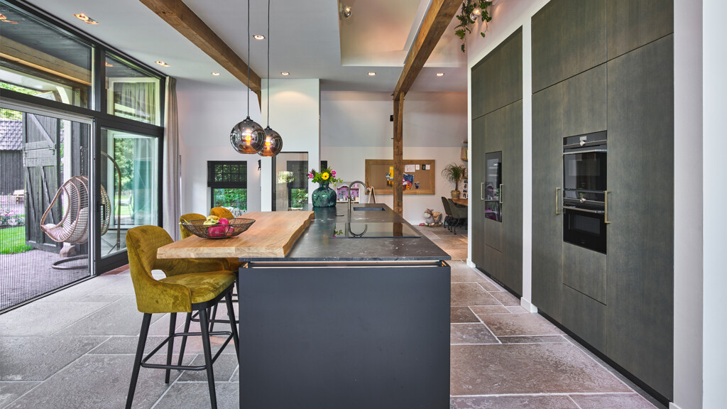 Grote open keuken van next125, het zwarte keukeneiland is voorzien van een houten bar. Ontdek Ekelhoff Küchen in Nordhorn