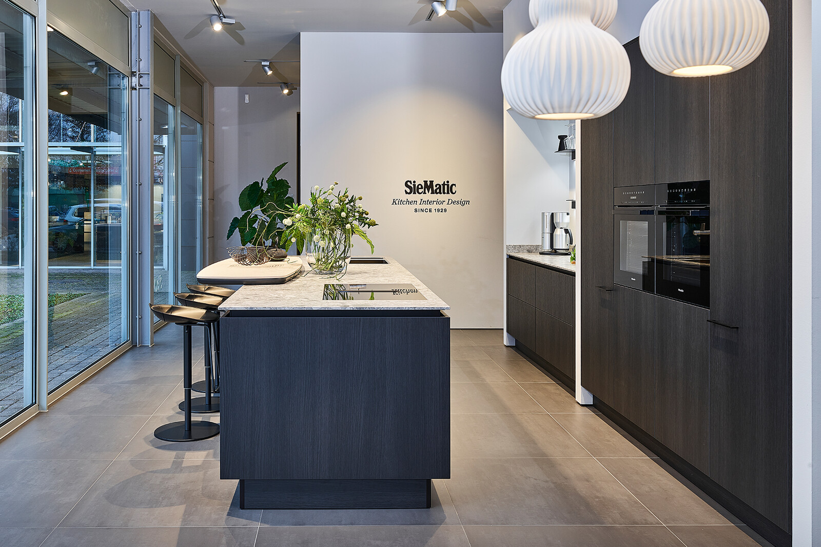 Showroomkeuken: Siematic S2 eilandkeuken met bar in donker Eiken Darjeeling, keramiek blad en Miele apparatuur