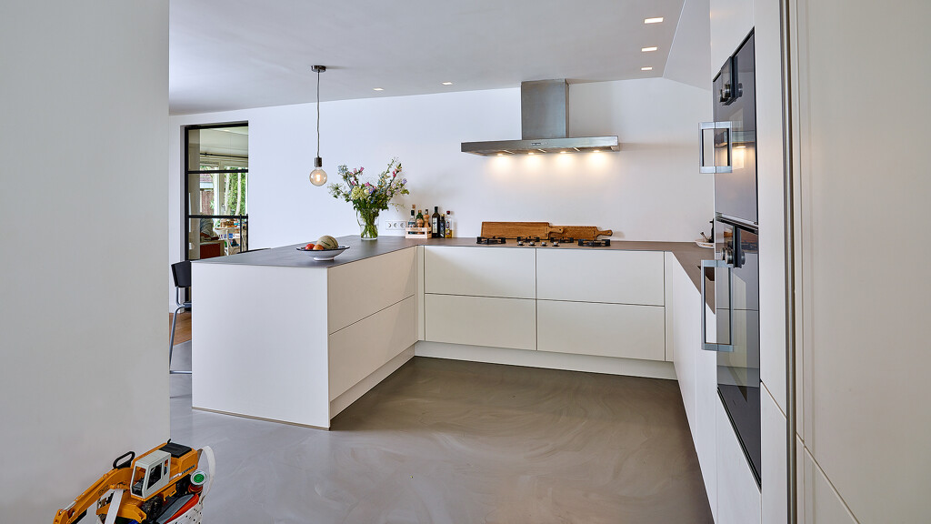 Greeploze u-keuken in magnolia met rvs keukenblad en Gaggenau apparatuur van Ekelhoff Keukens. Lees de keukenreview  met foto's. Keuken geinstalleerd in Het Gooi